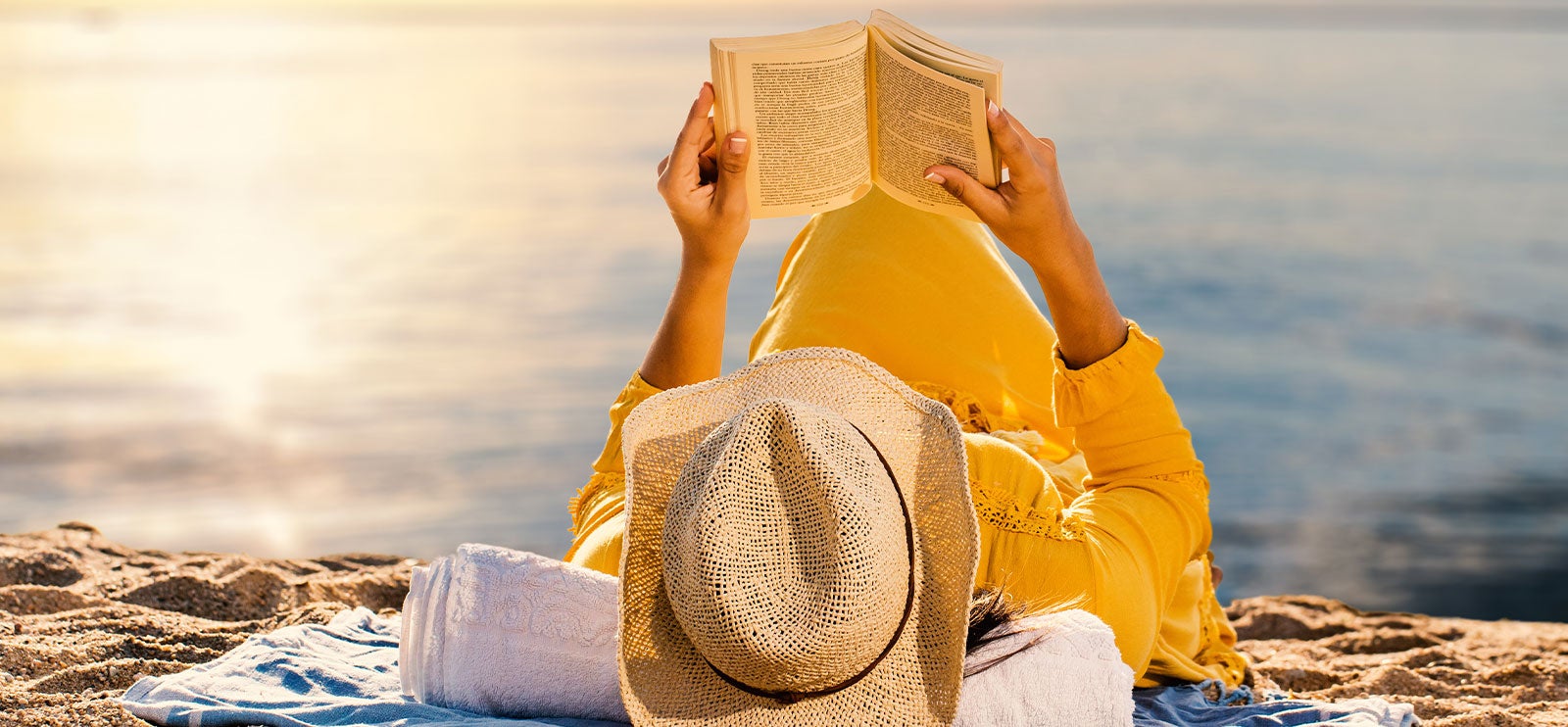Sommerens beste bøker Kvinne leser bok på stranden