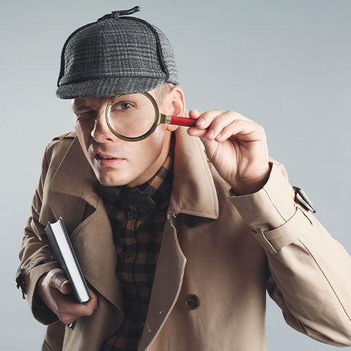 Mann kledd som en detektiv med katt og frakk. Han ser gjennom et forstørrelsesgladd.